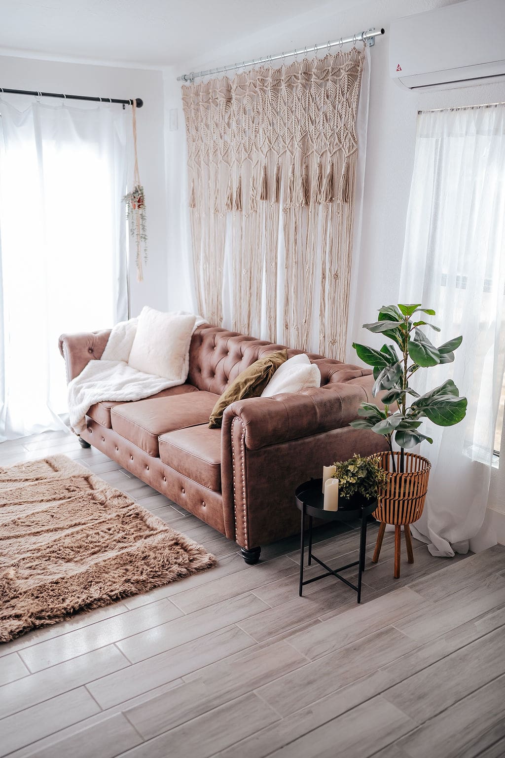 A living room with brown couch and plants