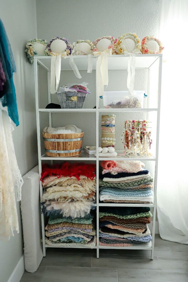 A white shelf with many different fabrics on it.
