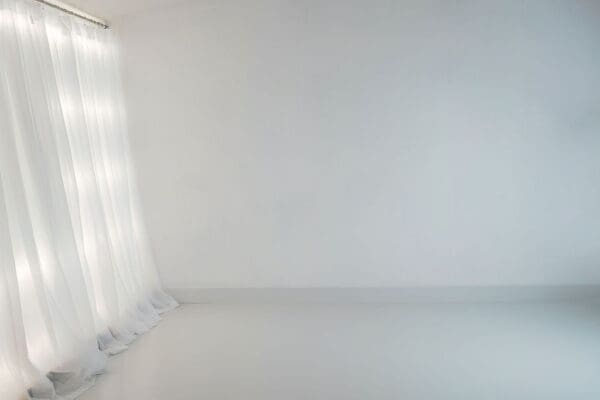 A white room with curtains and a curtain rod.