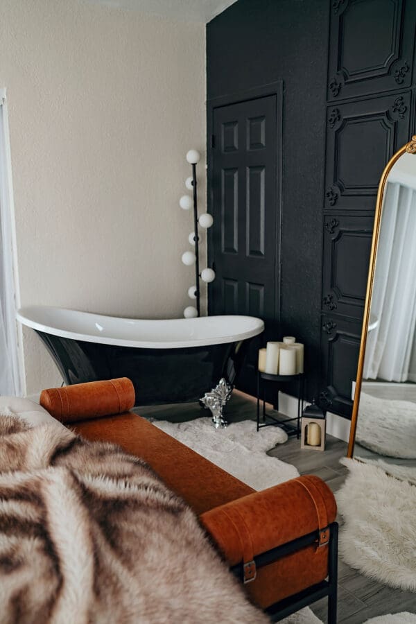 A bathroom with a tub, mirror and candles.