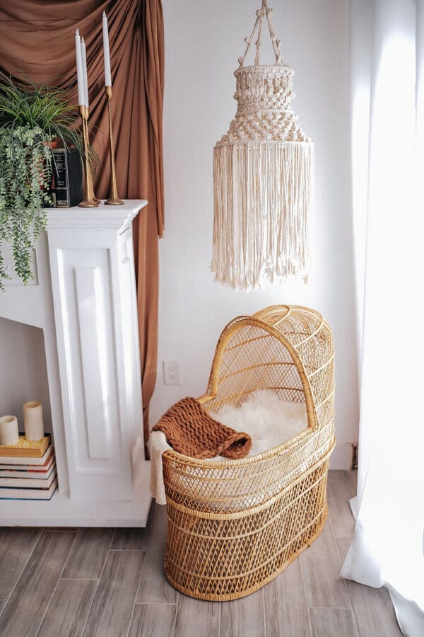 A baby crib in the corner of a room with a plant.