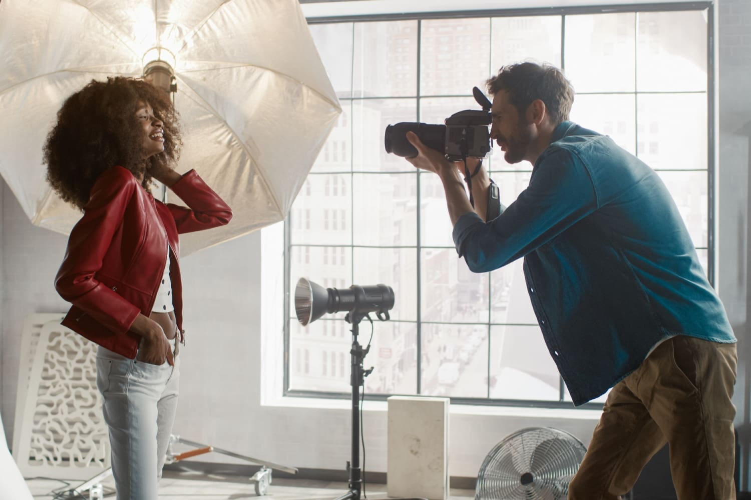 A man taking a picture of two women in front of an umbrella.