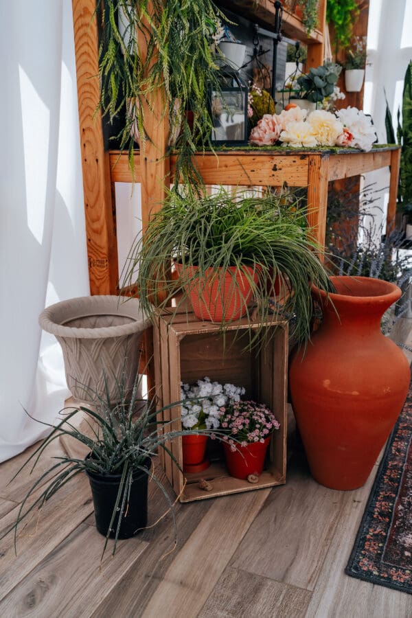 A wooden crate with plants in it next to two large vases.