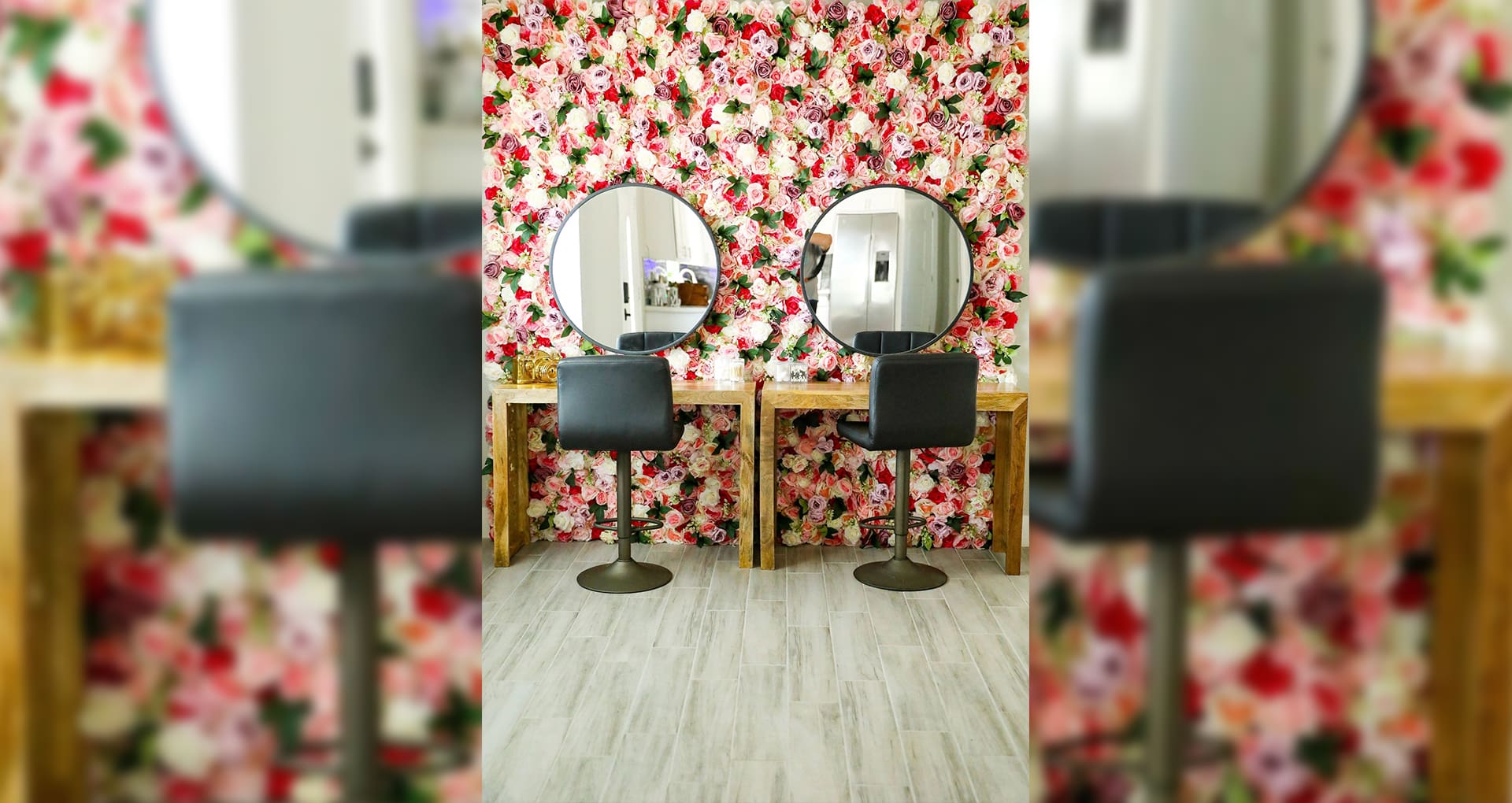 Two mirrors and a table in front of a floral wall.
