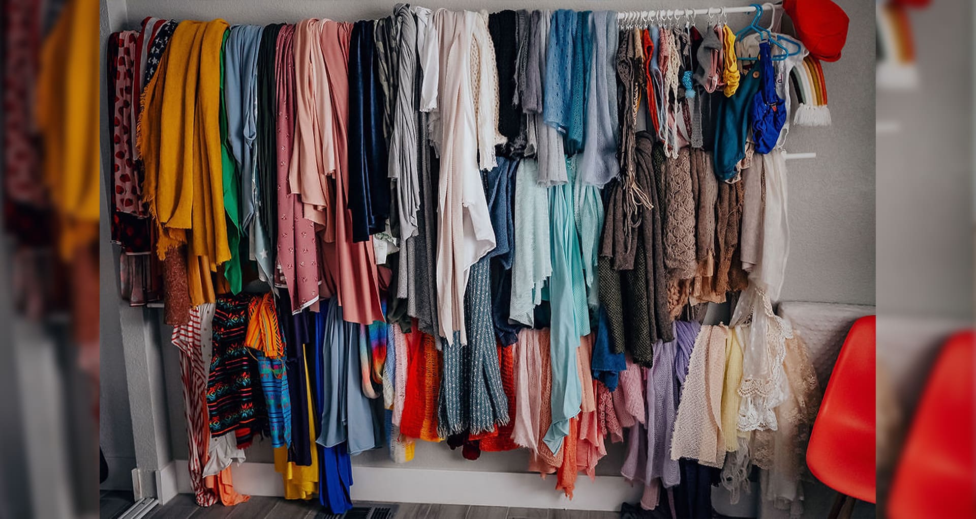 A closet full of different colored clothes hanging.