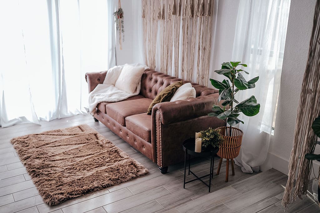 A living room with brown couch and white curtains